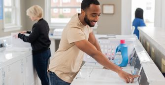 People happily doing laundry in a bright multi-family laundry room.