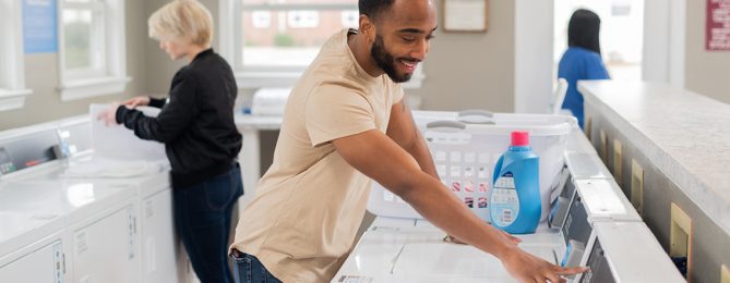 People happily doing laundry in a bright multi-family laundry room.