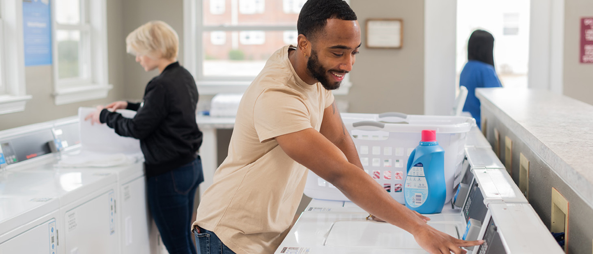 People happily doing laundry in a bright multi-family laundry room.